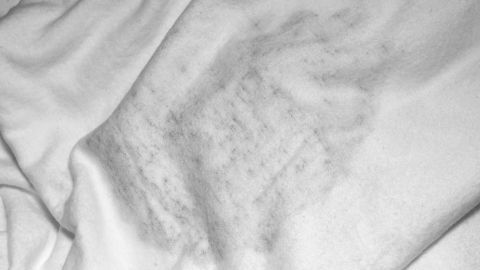 Ein weißes Textil zeigt schimmelige Stockflecken, die auf die Notwendigkeit zur Reinigung hinweisen.