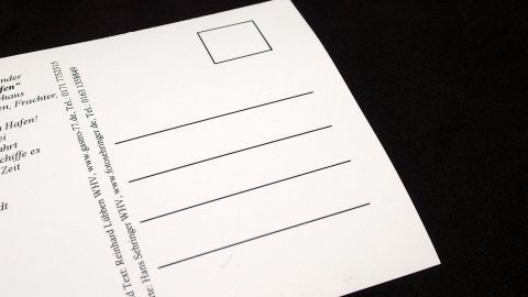 In diesem Artikel erfährst du, wie du beim Versenden von Briefen Geld sparen kannst. Die abgebildete Postkarte kann eine kostengünstige Alternative zu herkömmlichen Briefen sein. Lass dich inspirieren! Eine unbeschriebene Postkarte liegt auf einem schwarzen Untergrund und wartet darauf, für Briefe verwendet zu werden.