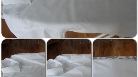 Ein weißes Hemd liegt auf einem dunklen Holztisch, während es gefaltet wird, um Platz im Koffer oder Schrank zu schaffen.