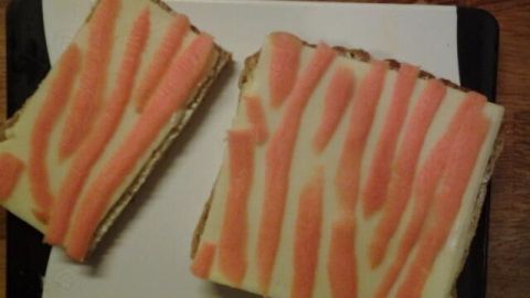 Zwei farbenfrohe Tigerstullen mit Käse und Möhren-Dekor liegen auf einem Schneidebrett in einer gemütlichen Küchenszene.