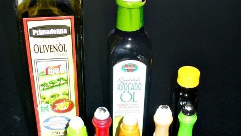 Eine Sammlung von leeren Roll-on-Stiften steht neben zwei Flaschen Öl auf einem Tisch, bereit zur Wiederverwendung.