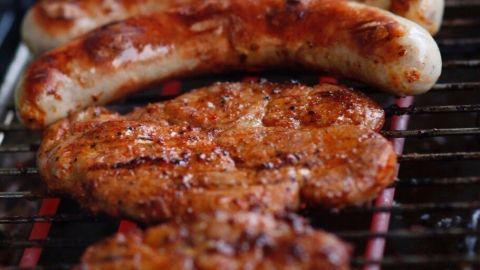 Auf dem Elektrogrill brutzeln gegrillte Würstchen und Fleischstücke, umgeben von einer gemütlichen Grillumgebung.