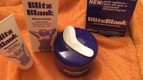 Enthaarungscreme steht auf einem Handtuch, während die Produkte BlitzBlank und Haarstop aufgeräumt sind, bereit zur Anwendung.