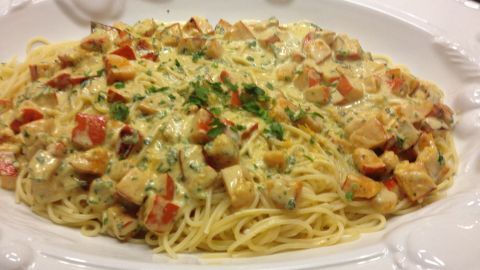 Eine cremige Kürbis-Mascarpone-Soße umhüllt Spaghetti, garniert mit gerösteten Mandeln auf einem eleganten Teller.