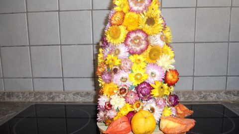 Bunte Trockenblumen in Form eines dekorativen Gebäcks stehen auf einem Tisch in einer modernen Küche.