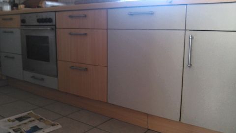 Eine Kücheneinheit aus Holz und Silber, deren Kanten und Ecken mit DC Fix tapeziert sind, steht vor einem Fenster.