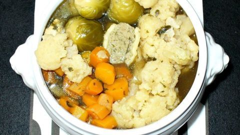 Eine weiße Schüssel mit Schlanksuppe wird präsentiert, gefüllt mit frischem Gemüse wie Karotten, Blumenkohl und Rosenkohl.