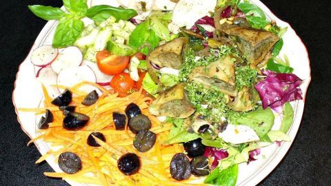Ein bunten Salatteller mit frischem Gemüse, Maultaschen und Hähnchenbrustfilet auf einem weißen Teller, ansprechend angerichtet.
