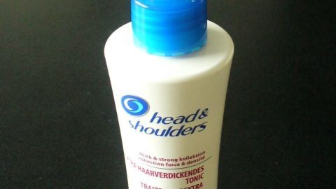 Ein Tonic von Head & Shoulders steht auf einem dunklen Tisch und dient der Haarverdickung für dünnes, lichtes Haar.
