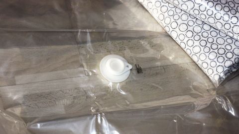 Gästebettwäsche ist in einer transparenten Vakuumverpackung mit einem Ventil zur Luftentfernung angeordnet.