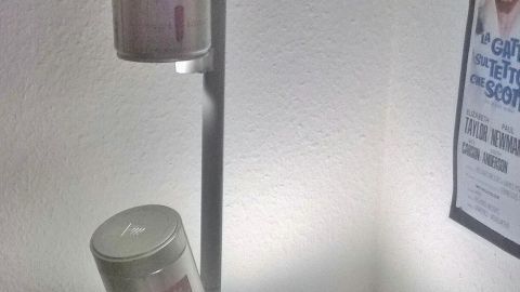 Eine Stehlampe aus Metall mit drei leuchtenden Gläsern steht in einem Raum und bietet modernes Lichtdesign.