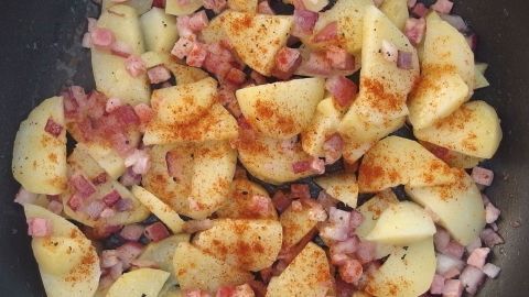 Bratkartoffeln bekommen eine appetitliche und schöne Farbe mit Paprika. Goldbraune Bratkartoffeln werden in einer Pfanne mit gewürfeltem Schinken und Paprikagewürz zubereitet.