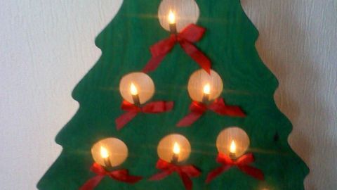 Ein stilisierter, grüner Weihnachtsbaum steht aufrecht und leuchtet mit Kerzen, geschmückt mit roten Schleifen.
