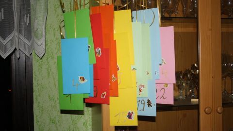 Bunte, hängende Taschen bilden einen Last Minute Adventskalender in einer gemütlichen Umgebung mit gläsernen Vitrinen.