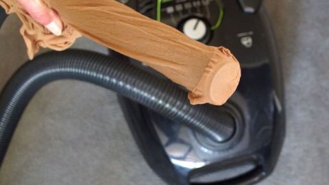 Ein Staubsauger wird benutzt, um kleine Teile wie Ohrringe aufzunehmen, während ein Socken über das Schlauchende gezogen wird.
