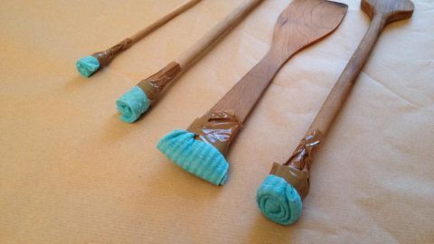Selbstgemachte Pinsel aus Kochlöffeln und Schwammtüchern stehen auf einem Tisch, bereit zum Malen oder Dekorieren.