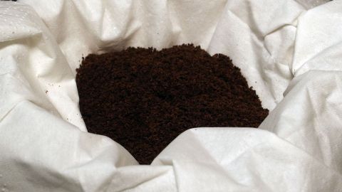 In einem Kaffeefilter liegen frisch gemahlene Kaffeebohnen, die zum Brühen in einer Küche vorbereitet werden.