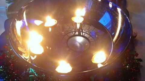 Ein glänzendes Schüsselchen mit schwimmenden Walnusskerzen leuchtet sanft, umgeben von festlicher Dekoration und Weihnachtsstimmung.