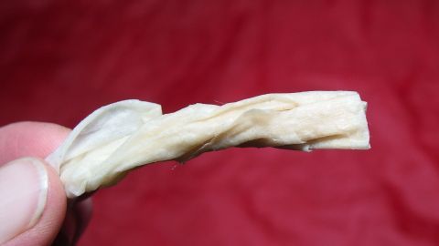 Ein Mensch hält ein Stück zerknülltes Material in der Hand. Es könnte als natürliche Hilfe gegen eine verstopfte Nase dienen.