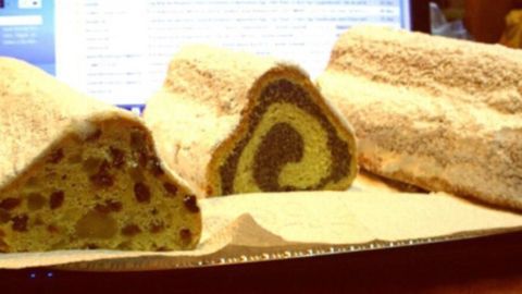 Butterstollen-Varianten liegen auf einer Tischplatte, während die durchsichtigen Scheiben mit Mohnfüllung und Nüssen präsentiert werden.