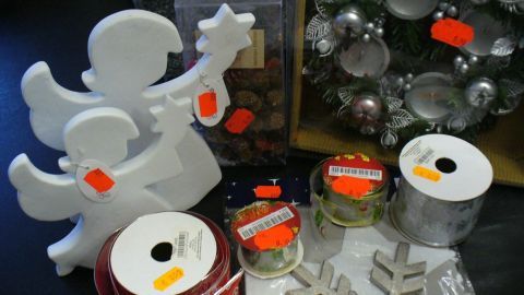 Dekorative saisonale Artikel, wie Engel und Geschenkbänder, liegen reduziert auf einem Tisch in einem festlichen Kontext.