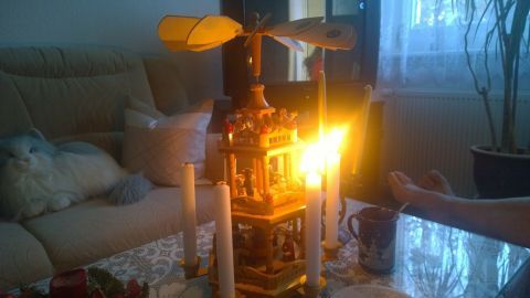 Die Weihnachts-Pyramide steht auf einem Tisch und leuchtet, während sie sich nicht dreht, umgeben von einer gemütlichen Wohnumgebung.