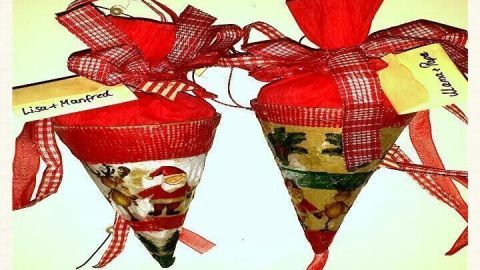 Zwei dekorativ verpackte Naschereien in Kegelform, geschmückt mit rotem Geschenkband und Etiketten.