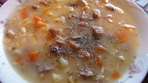 Eine herzhafte Spießbraten-Suppe in einer flachen Schale, gefüllt mit Gemüse und Gewürzen, appetitlich angerichtet.