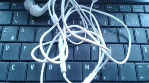 Kopfhörer, die sich ständig verknoten, können frustrierend sein. Im Artikel erfährst du nützliche Tipps, wie du verknotete Kabel vermeiden kannst, und so mehr Freude an deiner Musik hast. Ideal für jeden Musikliebhaber! Kopfhörer liegen verworren auf einer Tastatur, was das Problem von verknoteten Kopfhörern veranschaulicht.