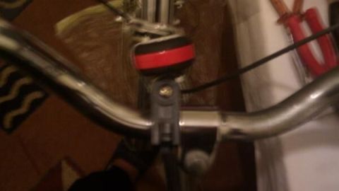 Ein Fahrradlenker mit einem Rostfleck wird in einem Innenraum betrachtet, während eine Person daran arbeitet.