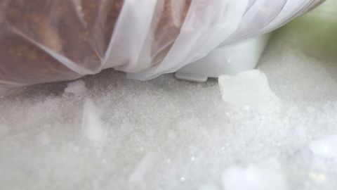 Gefriertüte liegt auf Eis im Gefrierschrank. Umgebung zeigt Frost und Eiskristalle im Gefrierprozess.