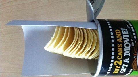 Eine Dose mit Chips steht auf einem Tisch, die Verpackung ist teilweise geöffnet und zeigt die gestapelten Chips darin.