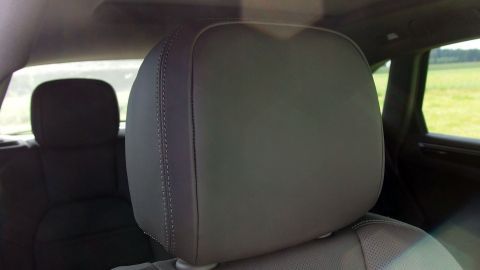Der Autositz mit Kopfstütze steht im Vordergrund, während der Fahrer beim Rückwärtsfahren durch die Rückscheibe blickt.