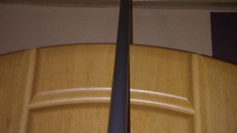Ein langer Besenstiel mit einem Reinigungsaufsatz reicht zur Decke, um Rauchbelag von Holzdecken zu entfernen.
