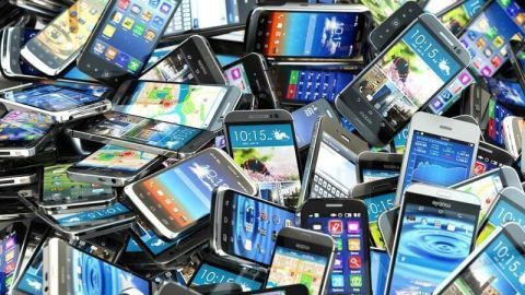 Zahlreiche alte Smartphones liegen übereinander und verdeutlichen die Auswirkungen geplanter Obsoleszenz in der Elektronikindustrie.