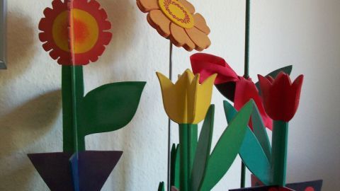 Bunte Papierblumen stehen in einer Vase und bringen Frühlingsgesteck-Atmosphäre in den Raum.