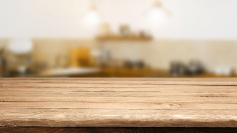 Ein blitzsauberer Esstisch aus Holz steht im Fokus, während die Küche im Hintergrund leicht verschwommen ist.
