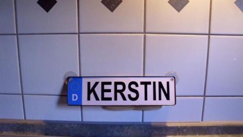 Ein Namenschild mit dem Text "KERSTIN" hängt an einer gefliesten Wand über der Küchenarbeitsfläche, die sauber bleibt.