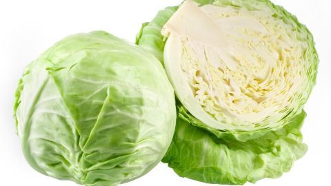 Kohlkopf liegt auf einer weißen Fläche, einer ganzen und einer halbierten Kopfkohl, bereit zum Vorbereiten für Kohlrouladen.