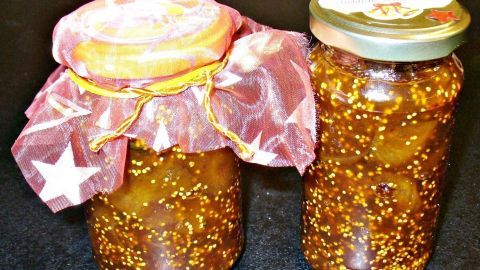 Zwei Gläser Feigen-Chutney stehen auf schwarzem Hintergrund, eines mit einem bunten, mit Sternen bedruckten Tuch bedeckt.