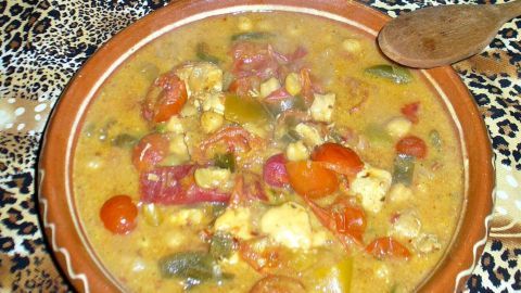 Eine Schüssel Tomatensuppe steht auf einem Tisch mit einem Leopardenmuster, umgeben von kulturellem Dekor.