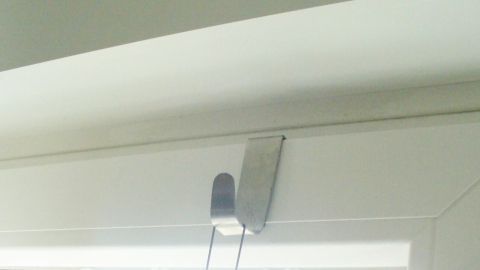 Ein Halter für eine Fensterdekoration ist am oberen Fensterrahmen montiert, ohne den Rahmen zu beschädigen.