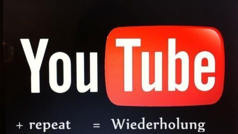YouTube-Logo mit den Wörtern "+ repeat" und "= Wiederholung", die die Funktion zum Wiederholen von Videos erklären.