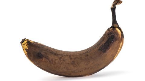Eine braune Banane liegt isoliert auf einem weißen Hintergrund und deutet auf die Verwendung von braunen Bananen hin.