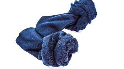 Alte Socken sind zu einem Knoten zusammengebunden und liegen auf einem weißen Hintergrund, bereit zur Wiederverwendung.
