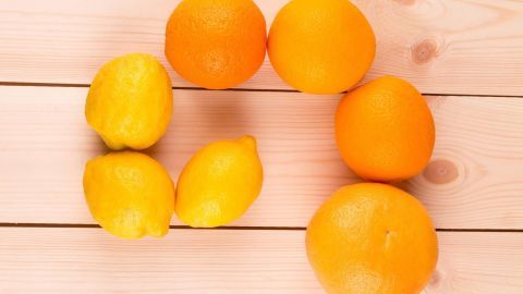 Zitronen und Orangen liegen auf einer Holzoberfläche. Sie sind frisch und leuchten in lebendigen Gelb- und Orangetönen.