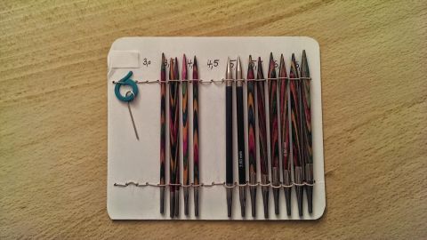 KnitPro Nadelspitzen stehen ordentlich in einer Halterung, mit einem Schlüssel zum Einstellen griffbereit, auf einem Holzuntergrund.