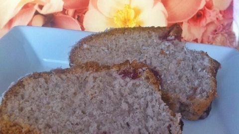 Saftiger Kirsch-Marzipan Gugelhupf auf einem weißen Teller, gelegentlich von einer blühenden, pastellfarbenen Hintergrund dekoriert.