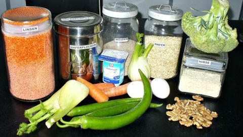Bunte Lebensmittel wie Linsen, Gemüse und Joghurt liegen auf einer schwarzen Fläche, die für eine ausgewogene Ernährung dient.