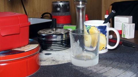 Auf dem Tisch stehen verschiedene Küchengeräte und Tassen, während jemand schnell aufräumt, um Ordnung zu schaffen.